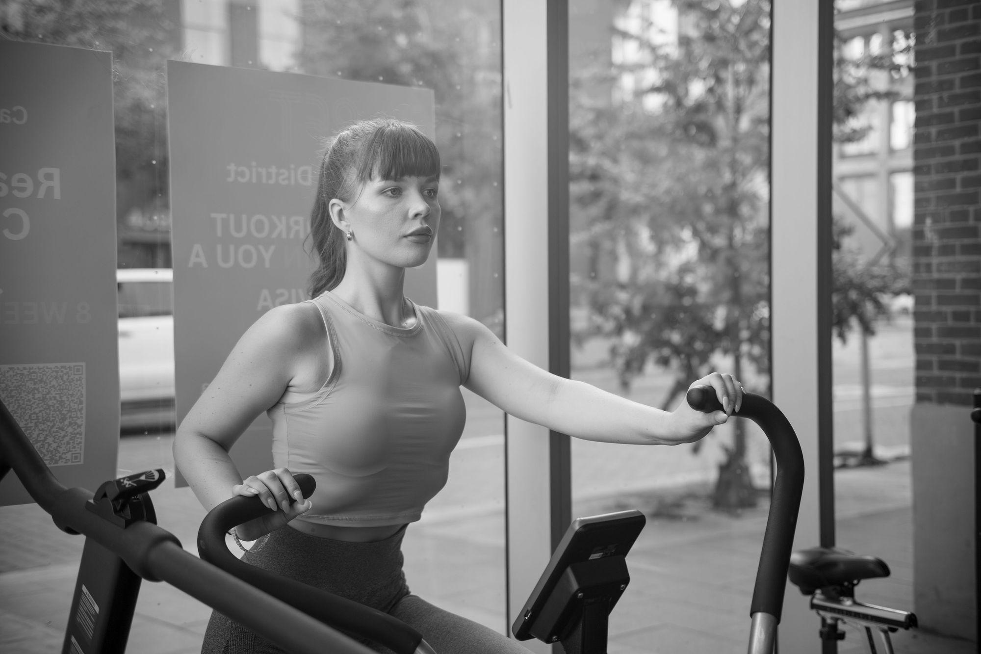 Client training on an air bike by a sunlit studio window